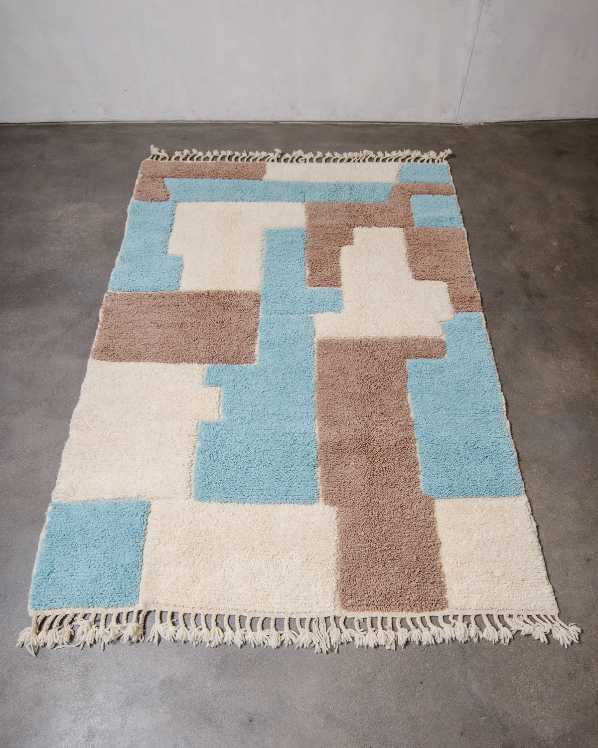 Berberlin Beniourain rug in fluffy wool, laying flat on concrete studio floor.